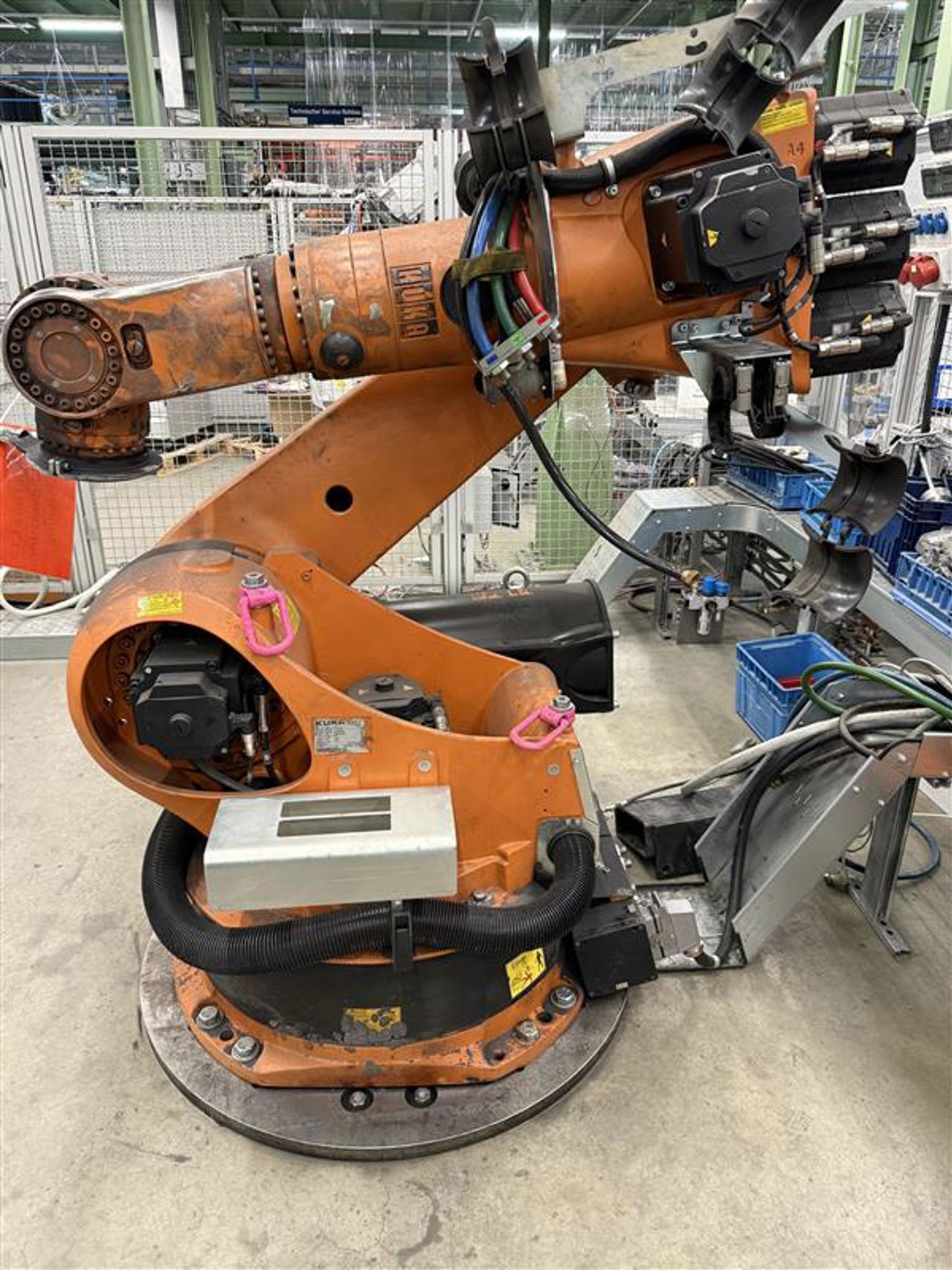 Robotbil som køyrer rundt i assemblyhallen og leverer delar til dei som jobbar der